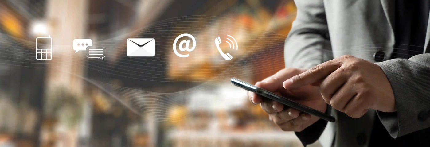 Person using a smartphone with communication icons above, blurred warehouse background